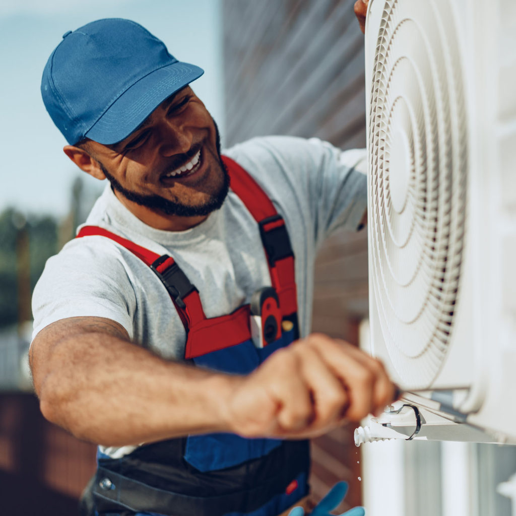 Air Conditioning repairman smiling as he works.